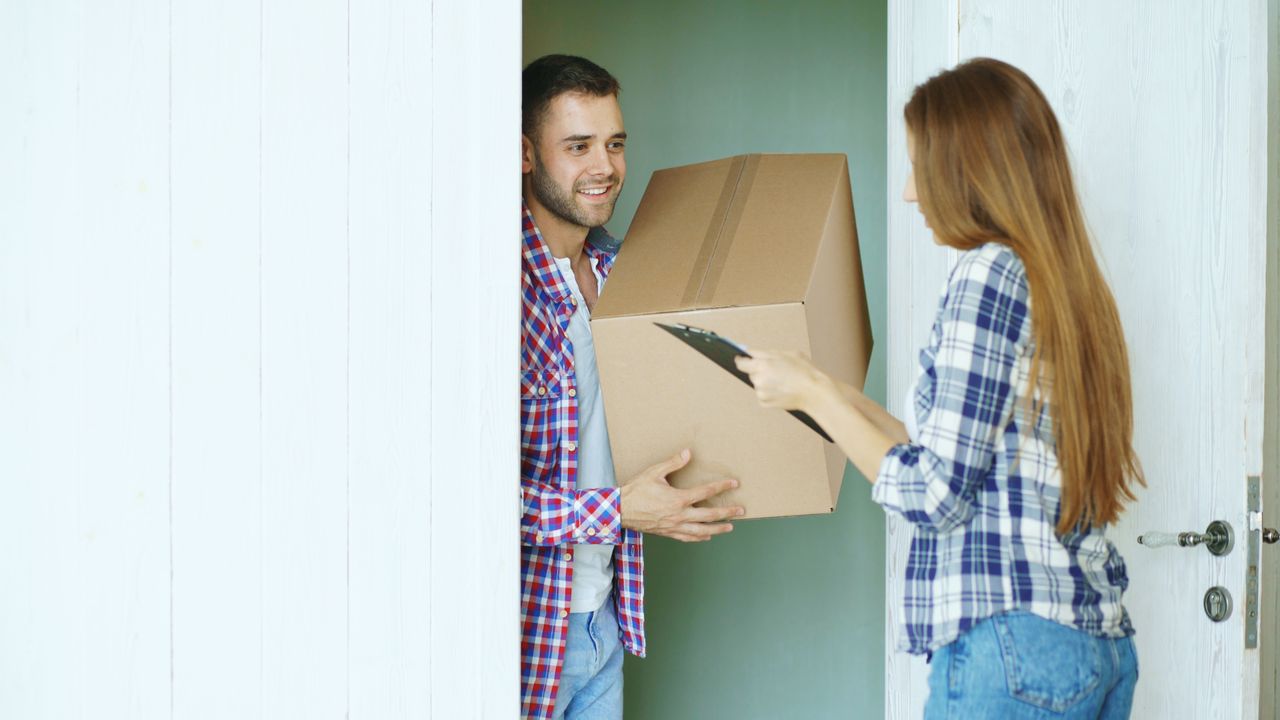 Two people exchanging a cardboard box at the door, representing delivery service.